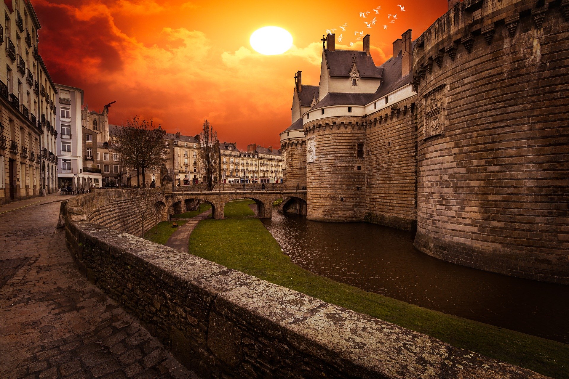 tendance marché immobilier nantes. Extrémité gauche du château avec des immeubles et un couché de soleil orange